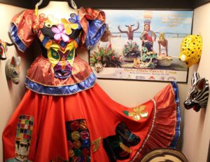 Further out shot of Carnaval Queen Story Dress. It is a colored taffeta and satin dress with multiple layers and colored fabrics. The dress tells a story with the many colorful patches and shapes.