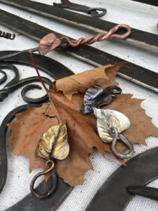 Metal leaves forged by Pat McCarty. The metal leaves are a rusted gold material and they rest atop an actual leaf.