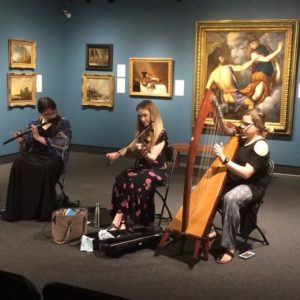 Photographed during a performance in the Museum of Art and Archaeology, from left to right is a flute player, violinist, and harp player.