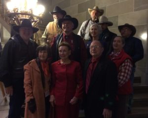 Jennie Cummings, in red, poses with First Lady Georganne Nixon and members of the Missouri Cowboy Poets Association at the Missouri Capitol after the 2016 Missouri Arts Awards. Jennie, center, wears a red matching suit with red beading around the neckline.