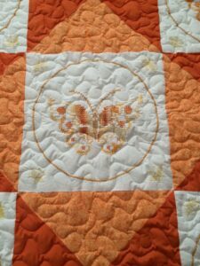 An orange and white quilt with embroidered butterflies