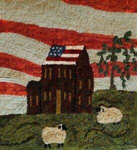 Hooked rug detail shows a saltbox style house with green lawn and two sheep resting. The house's roof and the background reference the American flag.
