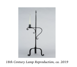 A black metal three-legged, table top lamp with a candle