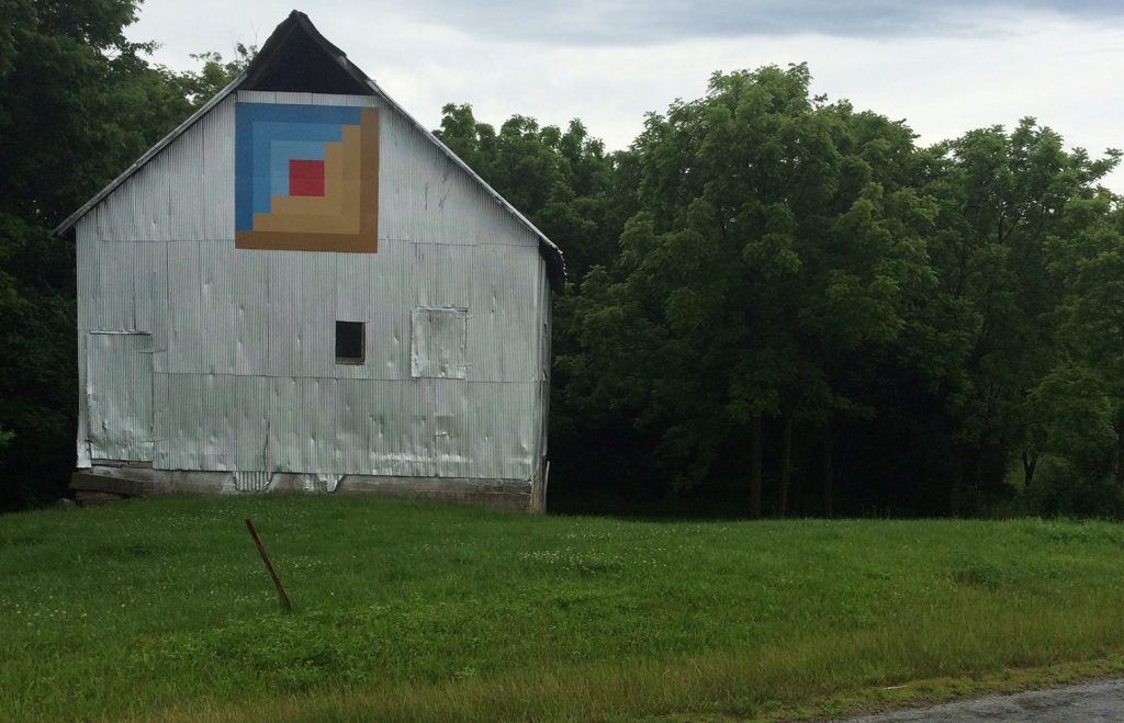 Tin covered barn with a blue, red, and brown quilt square 