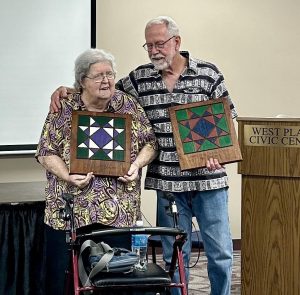 Sisco and Brown pose together with their colorful plaques featuring the Missouri Star quilt pattern.