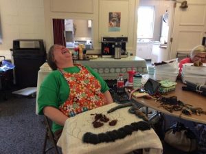 Woman in floral apron throws head back in laughter.